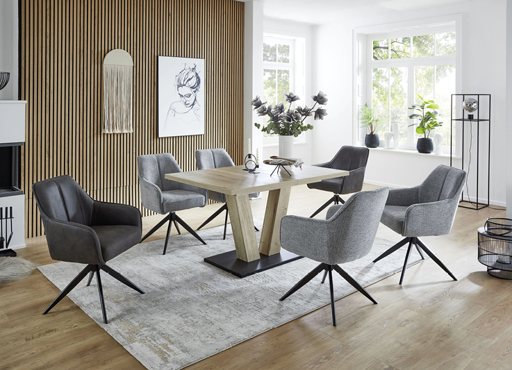 Esszimmer mit hoelzernem Esstisch und passenden Stuehlen in schwarz und grau.