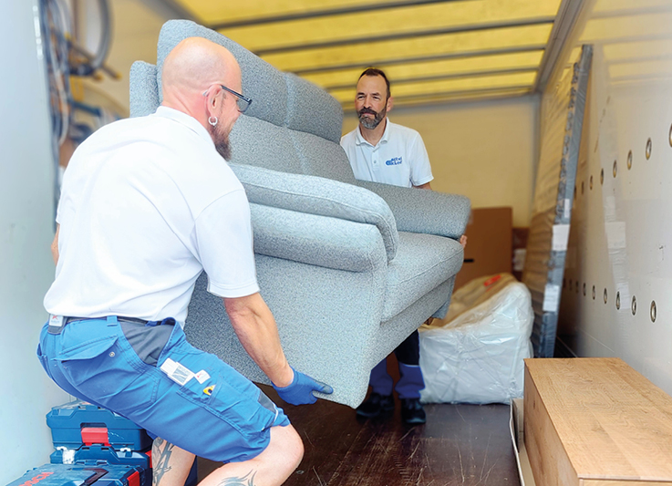 Monteure von Moebel Eickert beladen LKW mit einem Sofa zum Transport.