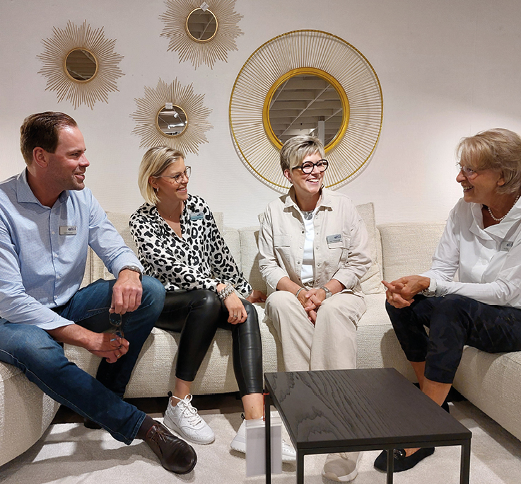 Mitarbeiter von Moebel Eickert sitzen gemeinsam auf Sofa.